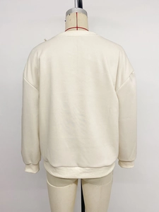 Detail view of the ribbed cuffs and hem on this cream oversized long sleeve sweatshirt