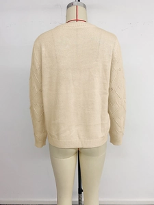Detailed knit texture showing heart hollow-out design on beige crewneck sweater