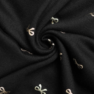 Gros plan détaillé du tricot noir doux avec un motif élégant de nœud doré imprimé