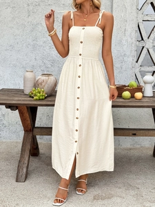 Close-up of smocked bodice and decorative front buttons on a beige summer maxi dress