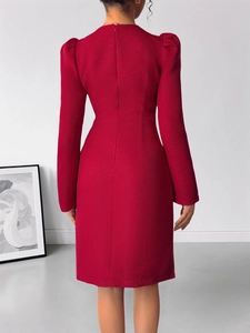Détail de la robe en tweed rouge avec nœud et perles sur l'élégant décolleté en V