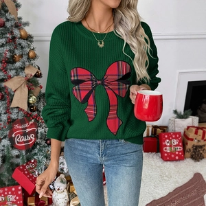 Detail shot of green Christmas sweater with red plaid bow in a festive holiday setting