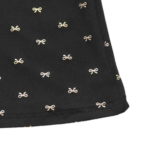 Détail de robe noire avec imprimé nœud doré et coutures renforcées de haute qualité