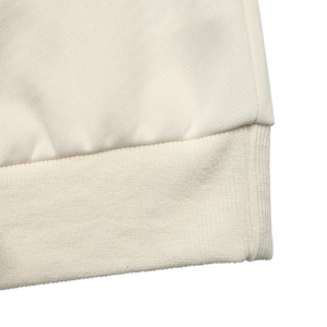 Detail of soft cream knit sweatshirt featuring high-quality ribbed cuffs and hem texture