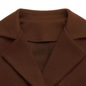 Dettaglio macro dell'elegante risvolto a lancia su questo cappotto di lana marrone scuro