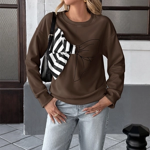 Detail of a dark brown sweatshirt featuring a striped patchwork bow and smooth cotton fabric