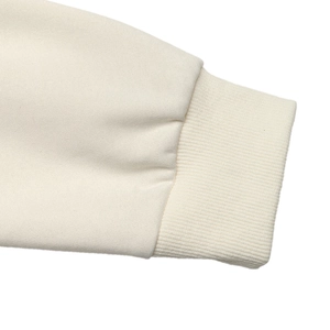 Detail shot of the cream-colored ribbed cuff and thick cotton jersey fabric of the sweatshirt