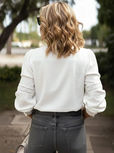 Detailed view of lace embroidery and hollow stitching on white blouse long sleeve