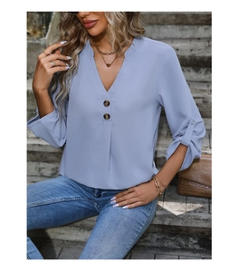 Detail of light blue long sleeve blouse with elegant button collar and draped fabric
