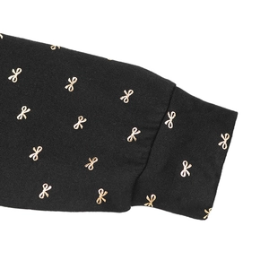 Détail du poignet en maille avec motif nœud doré scintillant sur robe noire chic