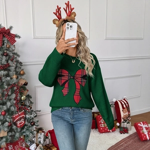 Detail of green Christmas sweater featuring a large red plaid bow on thick knit fabric