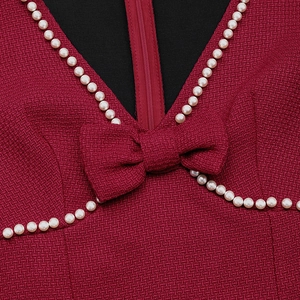 Détail du col en V sur robe en tweed bordeaux avec bordure perlée et nœud élégant