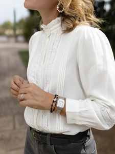 Detailed close-up of lace patchwork, hollow-out details, and pleated ruffles on a white shirt