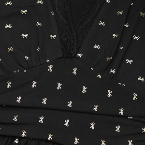 Détail de l'encolure en V avec dentelle noire et motifs de nœuds dorés sur la robe