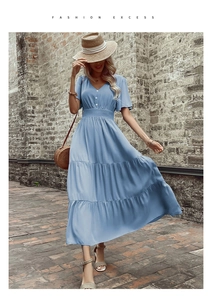 Dettaglio dell'abito azzurro con scollo a V, bottoni decorativi e vita alta elastica