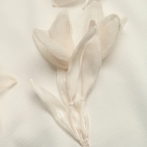 Macro shot of handcrafted 3D ivory organza floral applique on casual white sweatshirt