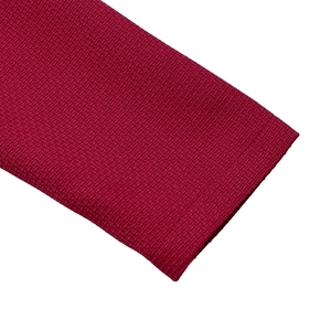 Détail de la manche d'une robe en maille rouge montrant la texture et la finition