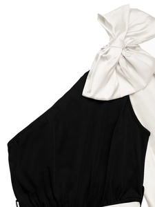 Détail du grand nœud en satin blanc sur une combinaison noire à épaule dénudée