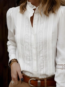 Detail of white blouse featuring ruffled stand collar and delicate lace embroidery details