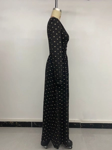 Détail de la robe noire à manches longues avec imprimés nœuds dorés et taille haute