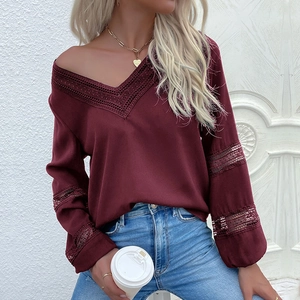 Detail of burgundy V-neck blouse with intricate lace cutouts and long sleeves