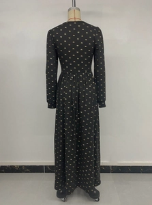 Détail d'une robe noire avec nœuds dorés et taille froncée sur un mannequin de couture