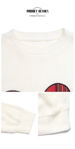Close-up of white knitted sweater featuring red plaid bow details and ribbed neckline
