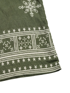 Close-up of ethnic white embroidery on dark green linen fabric with geometric patterns