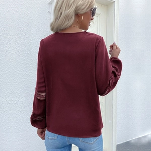 Detail of burgundy blouse back view showing intricate lace hollow-out stitching on sleeves