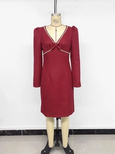 Détail de la robe rouge vin à col en V avec bordure en perles et nœud sur tissu tweed