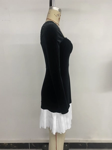 Side view of elegant black velvet dress with white pleated hem on a mannequin