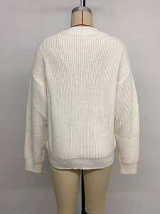 Rear view of white knit sweater showing thick vertical texture and ribbed hem detail
