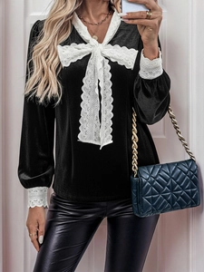 Detail of elegant black velvet blouse featuring white lace collar and oversized bow