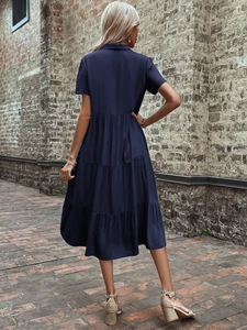 Back view of a navy blue lapel dress with a tiered skirt design on a vintage background