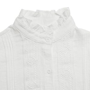 Close-up of the ruffled stand collar and geometric hollow embroidery on white blouse