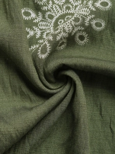 Detailed macro view of olive green linen fabric with white ethnic geometric patterns