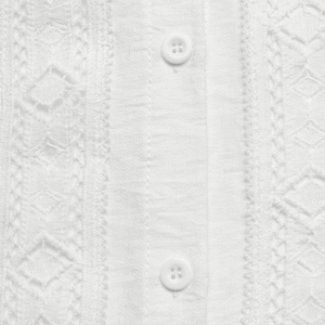 Detailed view of white shirt with intricate embroidery and hollow-out lace patterns