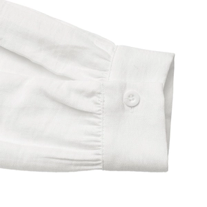 Detail shot of white shirt cuff featuring delicate pleated design and single button closure