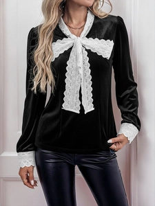 Close-up of elegant black velvet shirt with white lace bow and vintage collar detail