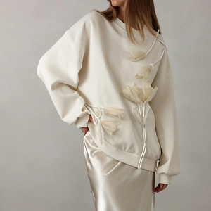 Detailed close-up of 3D floral tulip appliqué on a cream-colored long sleeve sweatshirt
