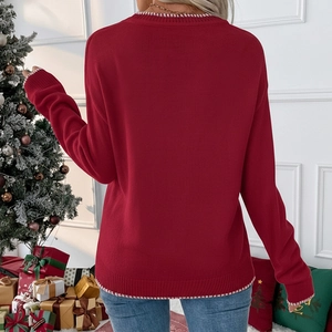 Detail of red knitted Christmas sweater with white stitched edges and festive bow pattern