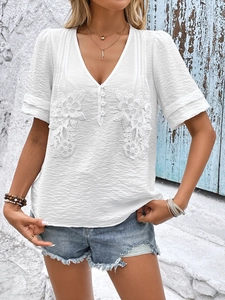 Detail of white textured fabric with floral lace embroidery on women's V-neck shirt