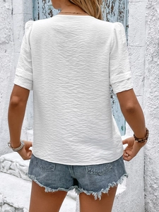 Rear view of white textured V-neck blouse showing puff sleeves and crepe fabric details