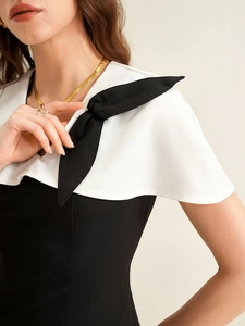 Détail de la robe contrastée noire et blanche avec un nœud à l'épaule et col capelet