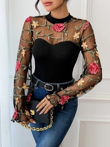 Detail of floral embroidery on sheer mesh long sleeve bodysuit with red and yellow flowers