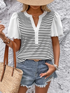 Detail of V-neck striped top with puff sleeves, paired with a straw bag and hat