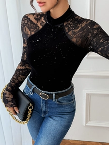 Detail of elegant black velvet bodysuit with lace sleeves and shimmering glitter finish
