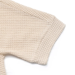 Gros plan détaillé du poignet tricoté beige avec motif gaufré évidé et complexe