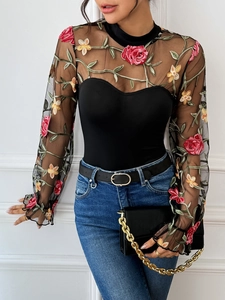 Detailed view of semi-transparent mesh bodysuit featuring vibrant floral embroidery and lace
