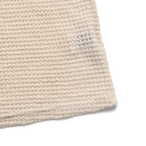 Vue détaillée du tissu en maille crochet beige montrant la texture alvéolée aérée
